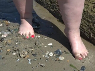Large nude gams with crimson pedicure walk along the bank of the sea, fetish.